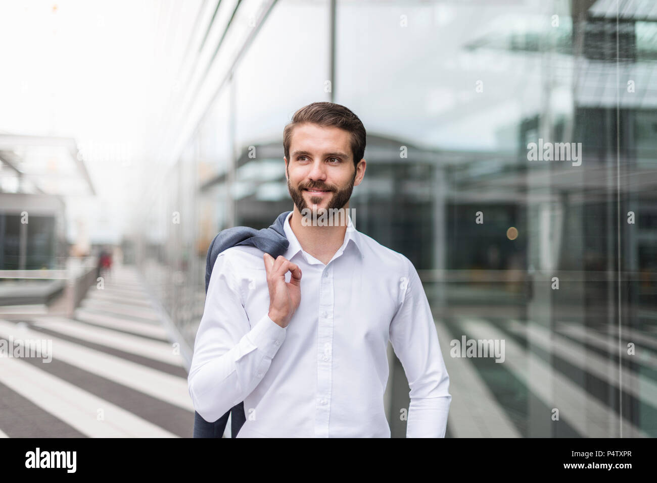 Portrait of smiling young businessman at glass facade Stock Photo