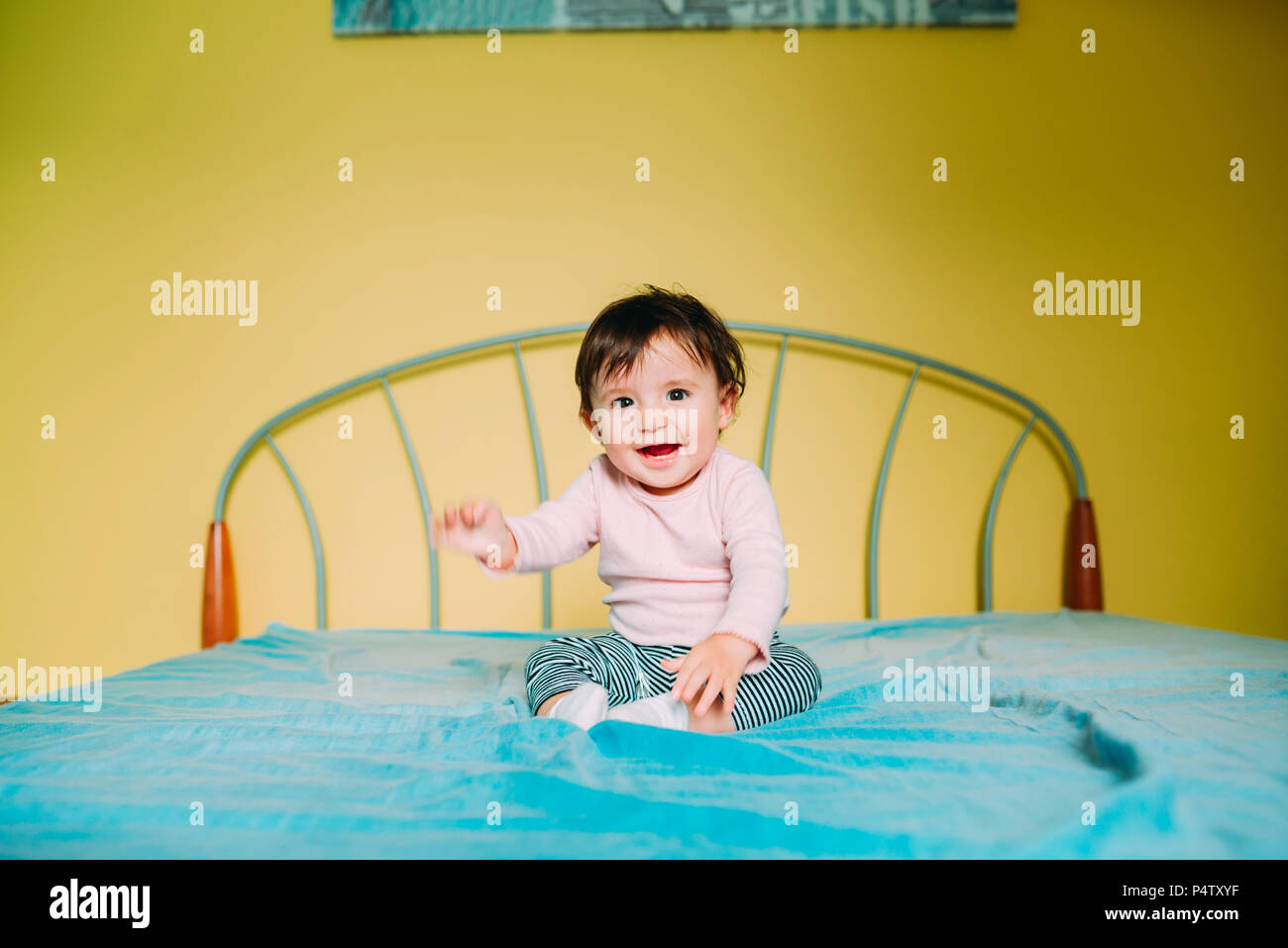 Happy baby girl sitting on the bed at home Stock Photo Alamy