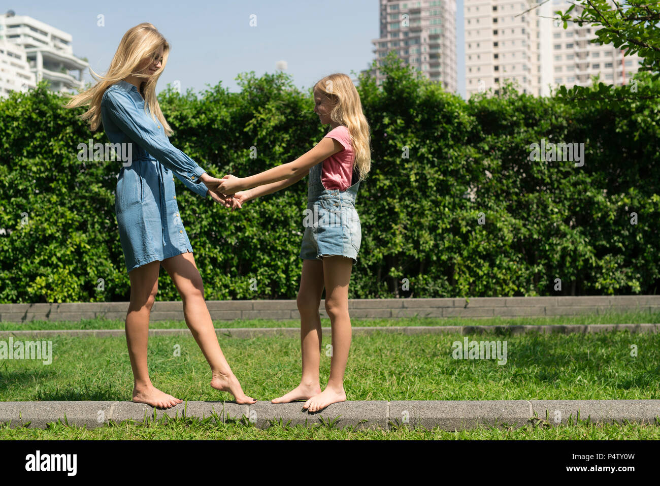 Happy mother and daughter holding hands in urban city garden Stock Photo