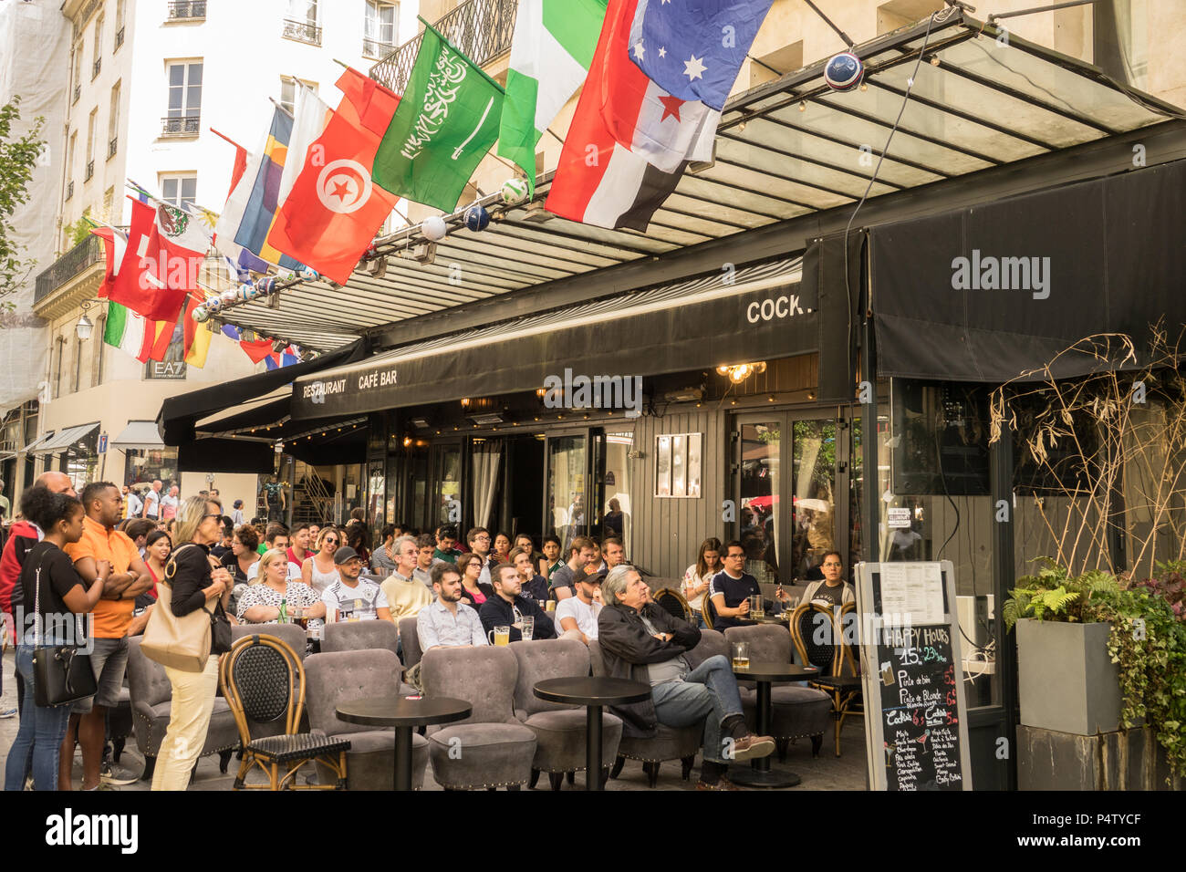 PARIS, FRANCE - 23 JUN 2018: People and supporters watch, the 2018 football world cup, at a coffee shop terrace in Paris Stock Photo