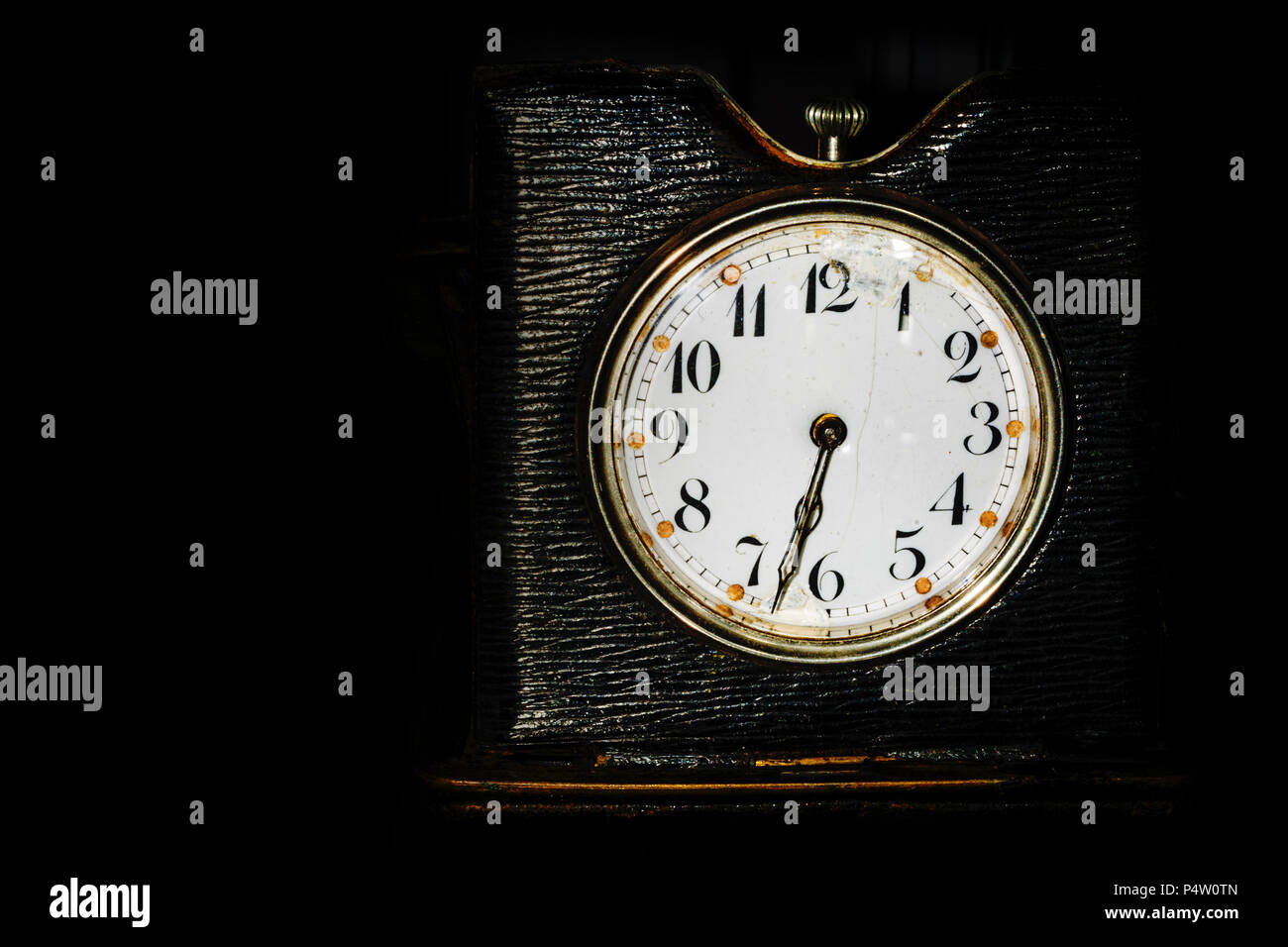 old dark-colored desk clock on a black background with space for text Stock Photo