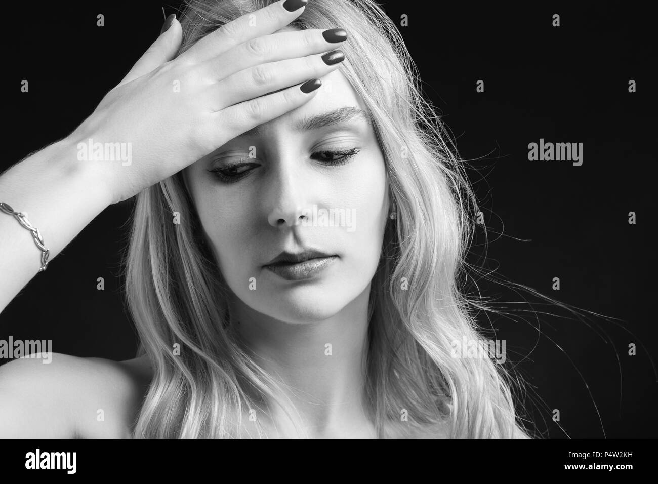 Beautiful young woman with headache touching her forehead, monochrome
