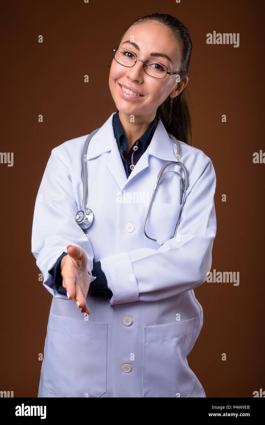 Studio shot of young beautiful woman doctor against brown backgr Stock ...