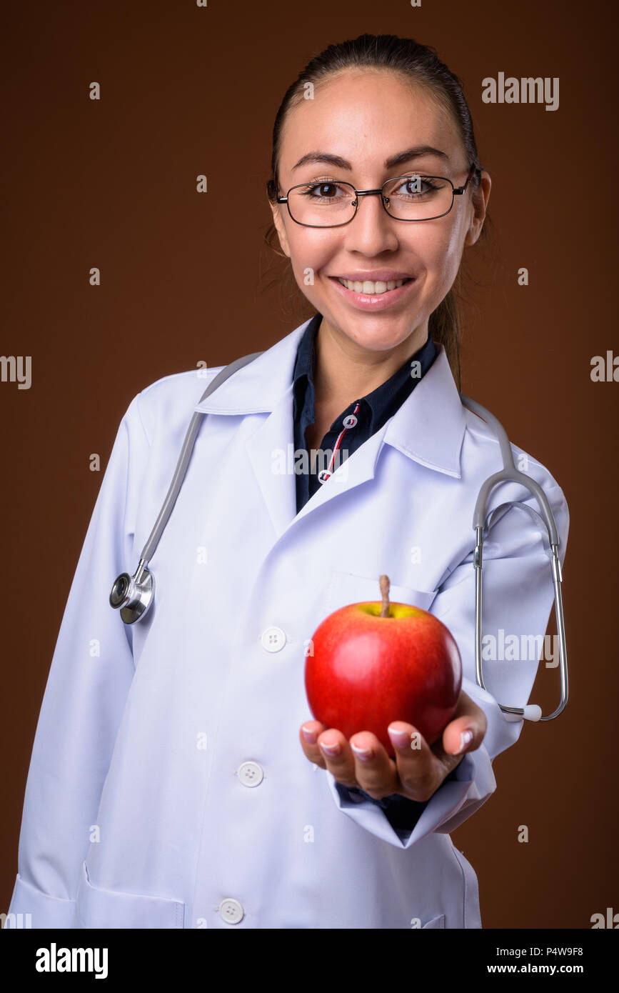 Studio shot of young beautiful woman doctor against brown backgr Stock ...