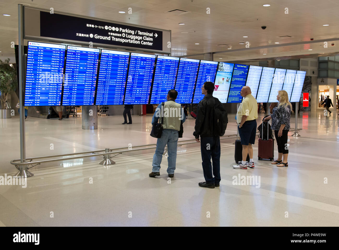 Passengers checking on flight schedule at airport Stock Photo