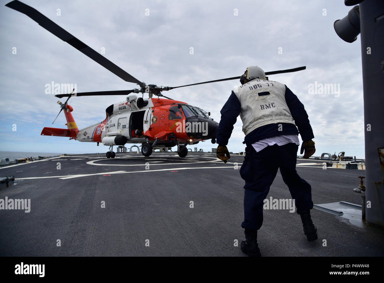 GULF OF ALASKA - A Chief Boatswain's Mate assigned to Arleigh Burke-class guided missile destroyer USS O'Kane (DDG 77) observes a U.S. Coast Guard MH-60T Jayhawk helicopter assigned to Air Station Kodiak, Alaska, landing during flight deck operations in the Gulf of Alaska. Northern Edge 2017 is Alaska's premiere joint-training exercise designed to practice operations, techniques, and procedures as well as enhance interoperability among the services. Thousands of participants from all the services; Sailors, Soldiers, Airmen, Marines, and Coast Guard personnel from active duty, Reserve and Natio Stock Photo