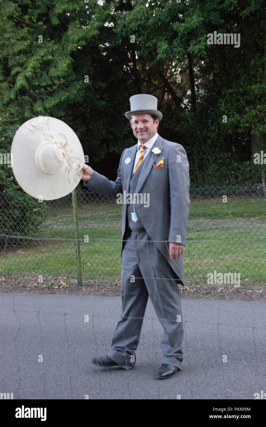 A gentleman at Ascot wearing top hat and tails and carrying a large