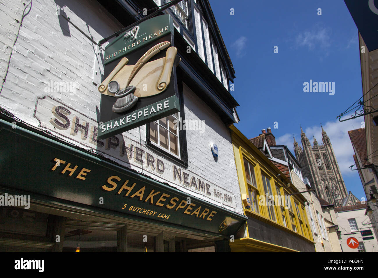 City of Canterbury, England. Shop and pub fronts on Canterbury’s Butchery Lane, with Canterbury Cathedral’s Bell Harry Tower in the background. Stock Photo