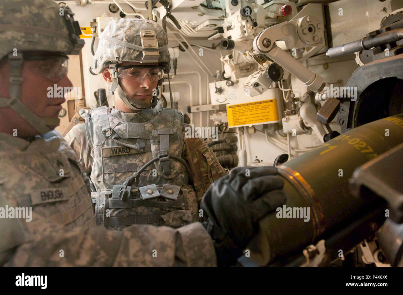 Pvt. Edward N. Ward, a La Habra, California native, assigned to Battery B., 4th Battalion, 27th Field Artillery Regiment, 2nd Brigade Combat Team, 1st Armored Division observes Cpl. Collin English, a Keys, Florida native, assigned to Battery B., 4-27 FA, 2nd BCT, 1st AD load an artillery round into the breach of a M109A6 Paladin cannon artillery system during Iron Focus May10 at the training site here. Iron Focus 17 training enables the commander to focus leadership, training, and resources on improving 2-1 AD’s combat readiness and worldwide operations during their transition from a Training  Stock Photo