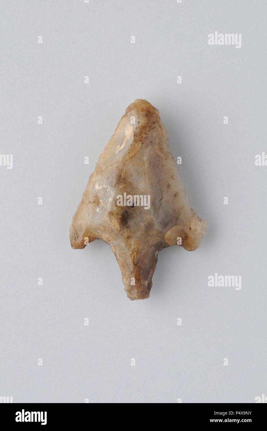 Flint arrowhead with fins and peduncle Width 22 mm Height 15 mm Thickness 4 mm- Chalcolithic period from the archaeological site of ' Esgaravita' in Alcalá de Henares - ' Burgo de Santiuste Museum ' (Madrid). SPAIN. Stock Photo