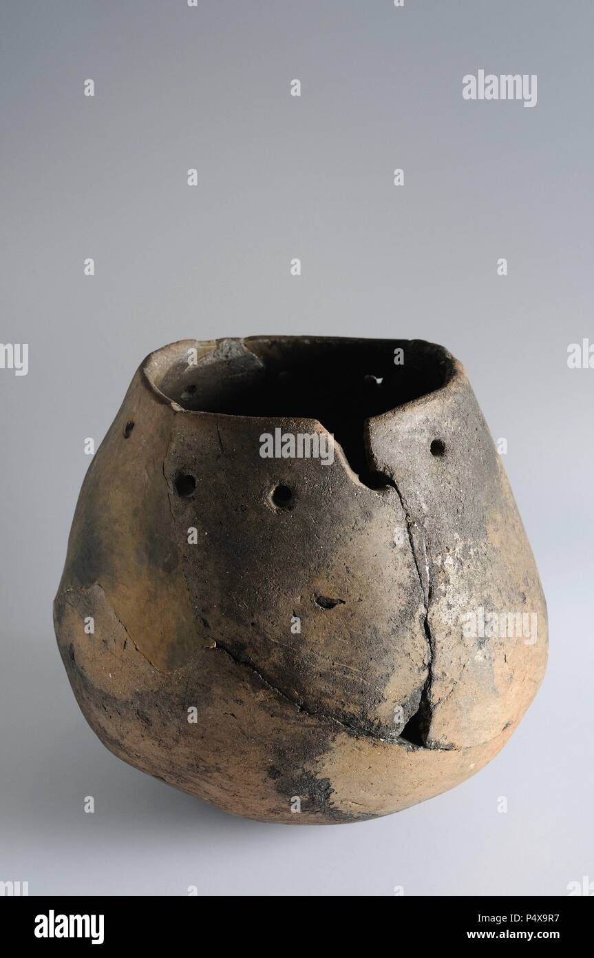 Ceramic pot , handmade and decorated with a series of perforations on the edge and concave base. 20.5 cm x 16 cm. Chalcolithic period from the archaeological site of ' Esgaravita' in Alcalá de Henares - ' Burgo de Santiuste Museum ' (Madrid). SPAIN. Stock Photo