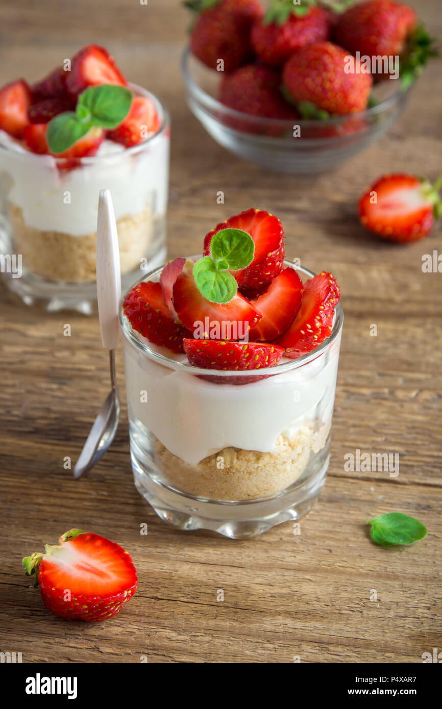 Strawberry trifle mini dessert in glasses with fresh strawberries and cream cheese on wooden