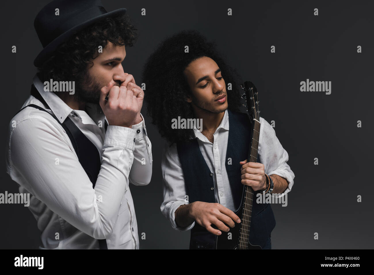 duet of musicians playing acoustic guitar and harmonica on black Stock