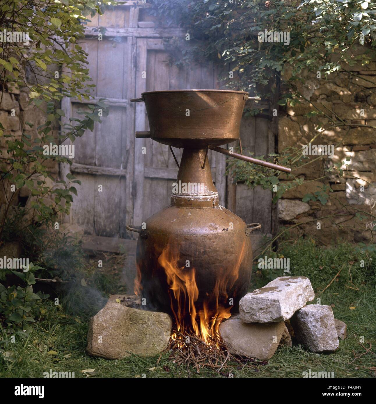 ELABORACION DEL AGUARDIENTE. El fuego actuando sobre el hallejo fermentado que se halla en el recipiente inferior de la alquitara. Navarra. Stock Photo