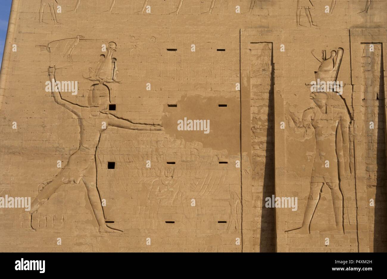Temple of Horus. The pharaoh Ptolemy XII Neo Dionysos sacrificing prisoners to the god Horus. Main entrance. First pylon. Detail. Edfu. Egypt. Stock Photo