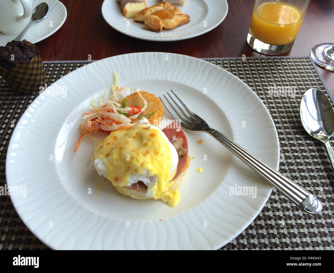 PULAU LANGKAWI, MALAYSIA - APR 6th 2015: Eggs Benedict is a traditional American breakfast or brunch dish with bacon, ham, a poached egg, and hollandaise sauce. Meal on a white plate in a luxury hotel restaurant Stock Photo