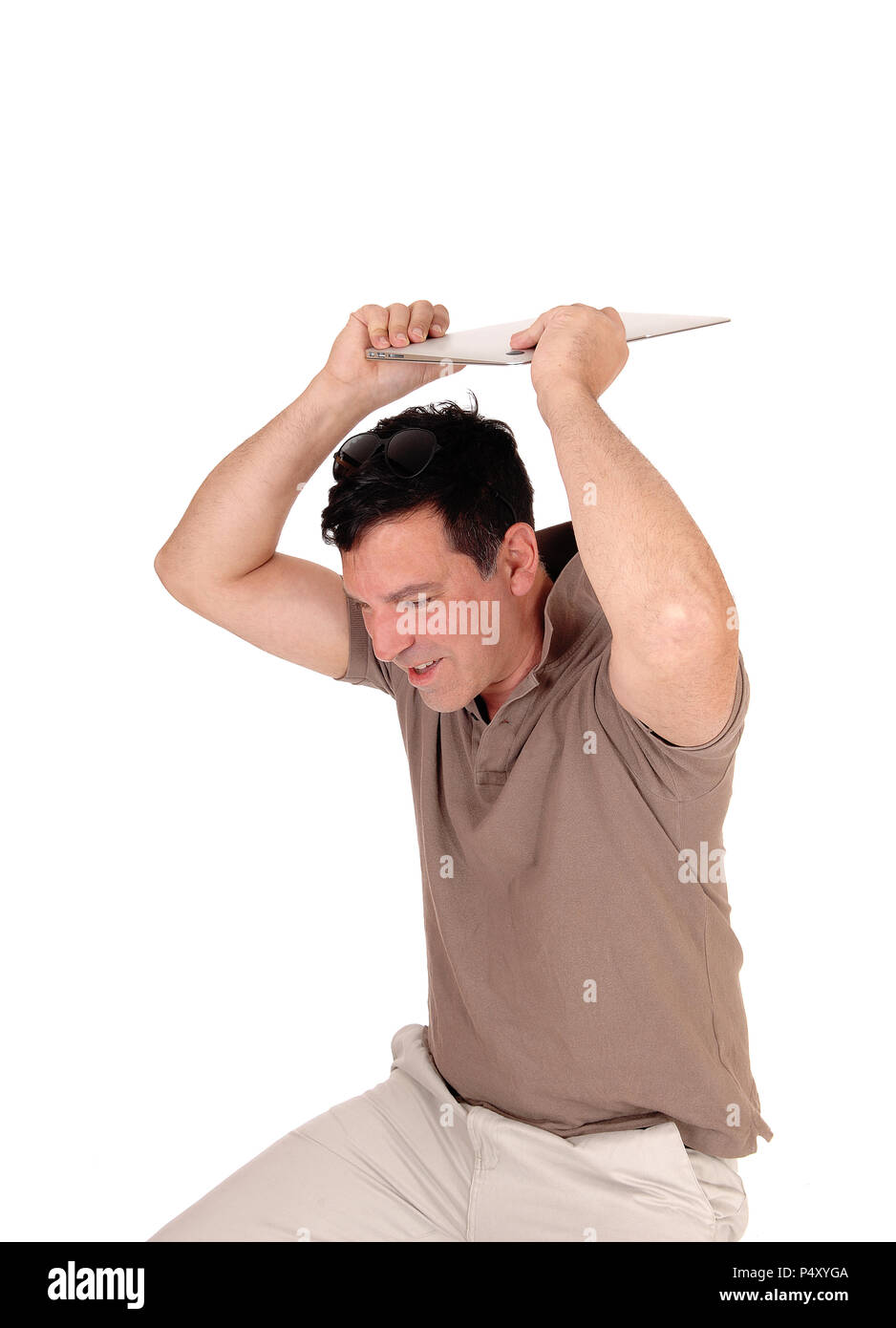 A very frustrated man sitting on a chair and likes to throw away his new laptop, holding it over his head, isolated for white background Stock Photo