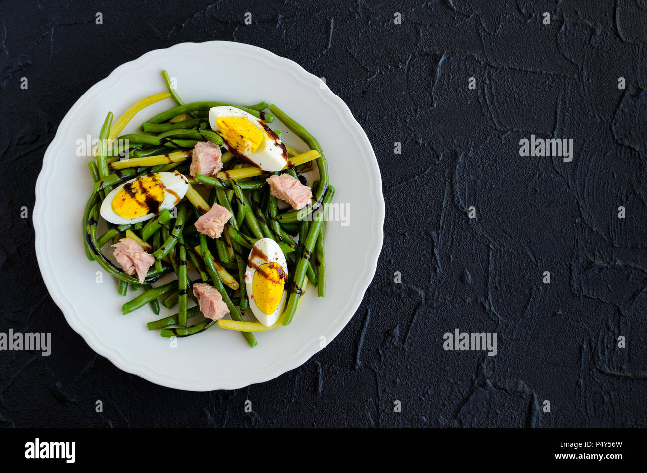 Summer warm salad with cooked green beans, tuna, boiled eggs and sauce