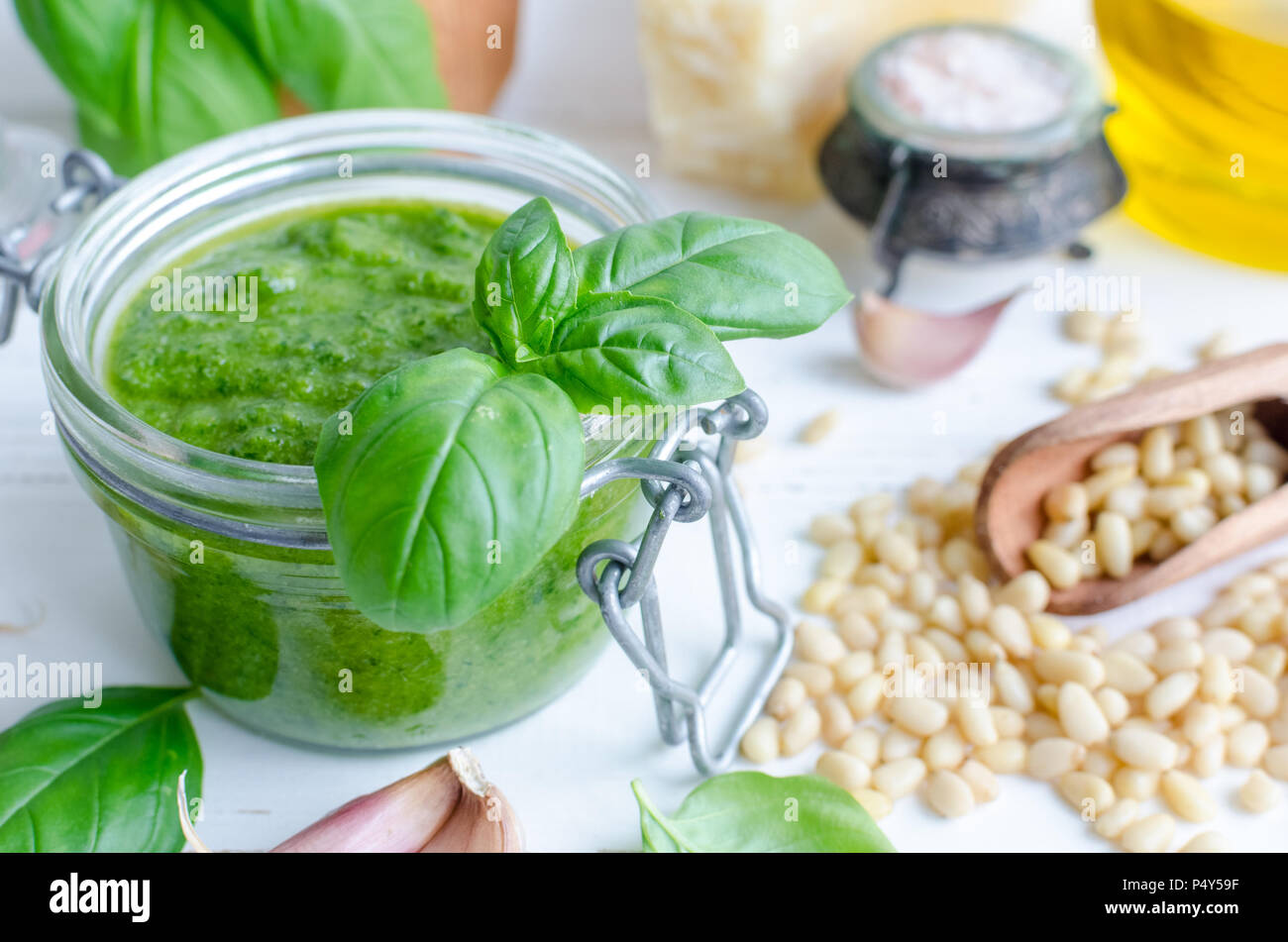 Pesto genovese traditional Italian green basil sauce with raw ingredients on white wooden
