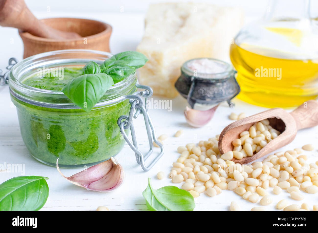 Pesto genovese traditional Italian green basil sauce with raw ingredients on white wooden