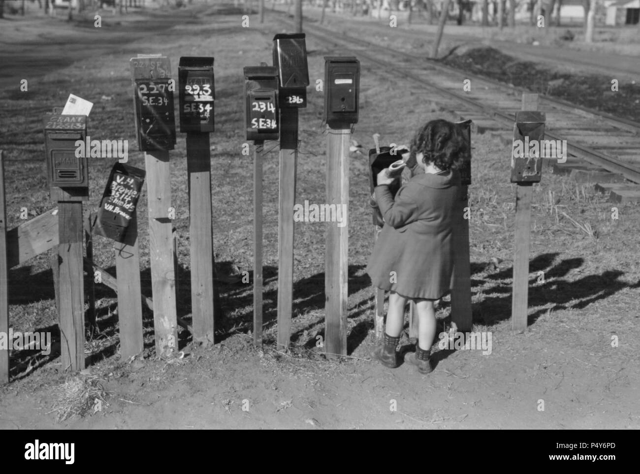 Little Girl Getting Mail from Mailbox, Suburb of Oklahoma City, Oklahoma, USA, Russell Lee, Farm Security Administration, February 1940 Stock Photo