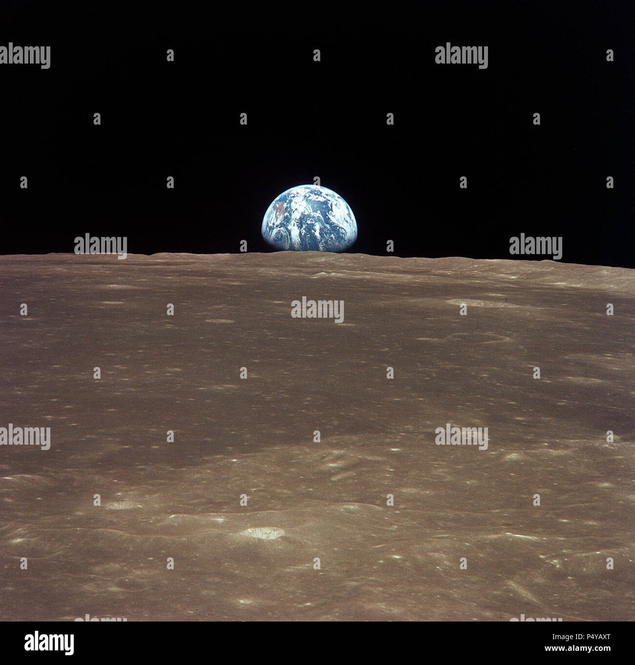 This view from the Apollo 11 spacecraft shows Earth rising above the moon's horizon. The lunar terrain pictured is in the area of Smyth's Sea on the nearside Stock Photo