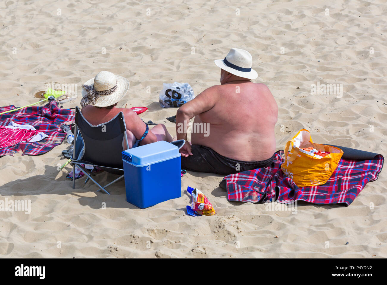 Bournemouth, Dorset, UK. 23rd June 2018. UK weather: crowded beaches on a lovely hot sunny day as visitors head to the seaside to make the most of the sunshine as temperatures rise for the heatwave. Couple sunbathing on the beach - overweight fat man Stock Photo