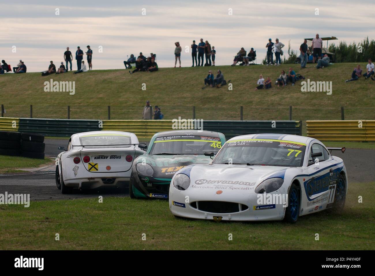Dalton on Tees, England, 23 June 2018. Rookies Jamie Osborne, number 46, of WDE and Conner Garlick, number 77, a privateer driving on the grass to avoid a spinning car driven by rookie Ben O’Hare in Round 11 of the Ginetta Junior Championship at Croft. Credit: Colin Edwards/Alamy Live News. Stock Photo