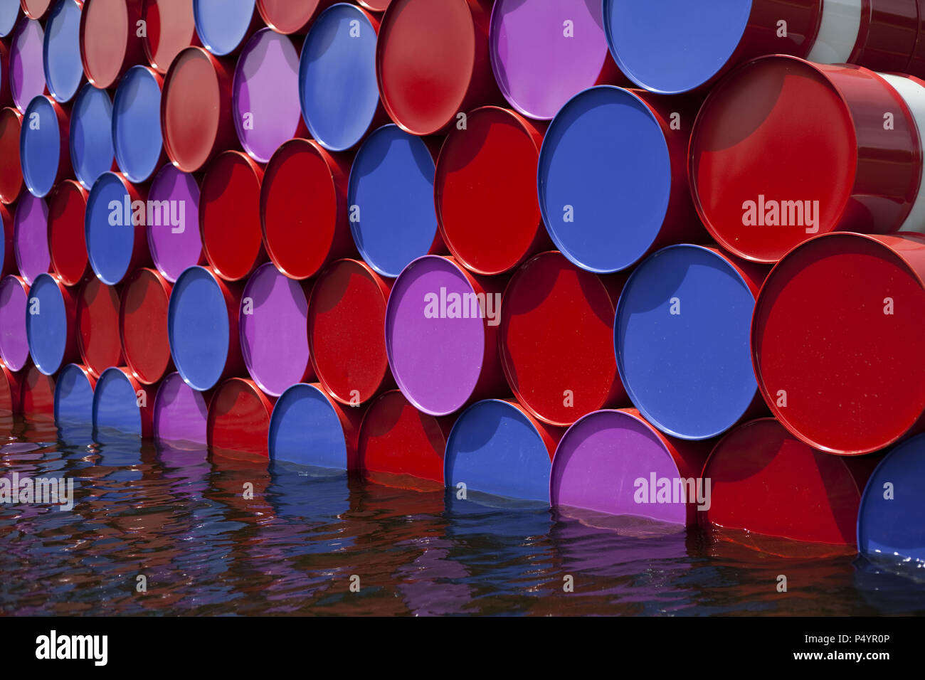 London, UK. 23 June 2018 The Mastaba, a temporary sculpture made of stacked barrels in Serpentine Lake in Hyde Park, is made by one of the world's most celebrated artists, famous for ambitious large scale works. Christo and his late wife Jean-Claude took an inspiration from ancient mastabas (benches) structures that originated in first urban civilisatons of Mesopotamia. Twenty metres in height, the structure consists of 7506 horizontally-stacked coloured barrels. The sculpture coincides with Serpentine Galleries exhibition of Christo and Jeanne-Claude's use of barrels in their work over th Cre Stock Photo