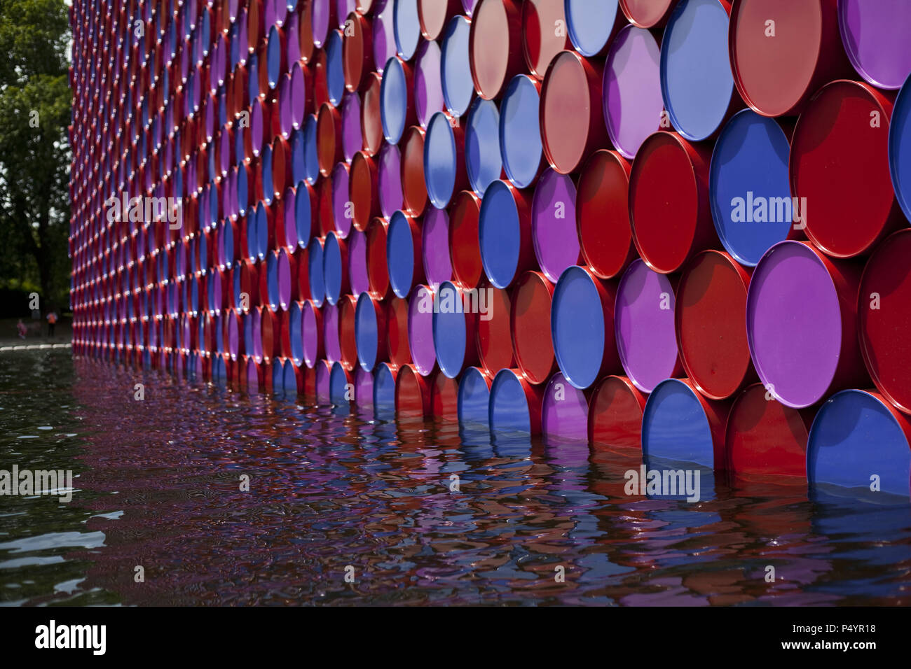 London, UK. 23 June 2018 The Mastaba, a temporary sculpture made of stacked barrels in Serpentine Lake in Hyde Park, is made by one of the world's most celebrated artists, famous for ambitious large scale works. Christo and his late wife Jean-Claude took an inspiration from ancient mastabas (benches) structures that originated in first urban civilisatons of Mesopotamia. Twenty metres in height, the structure consists of 7506 horizontally-stacked coloured barrels. The sculpture coincides with Serpentine Galleries exhibition of Christo and Jeanne-Claude's use of barrels in their work over th Cre Stock Photo