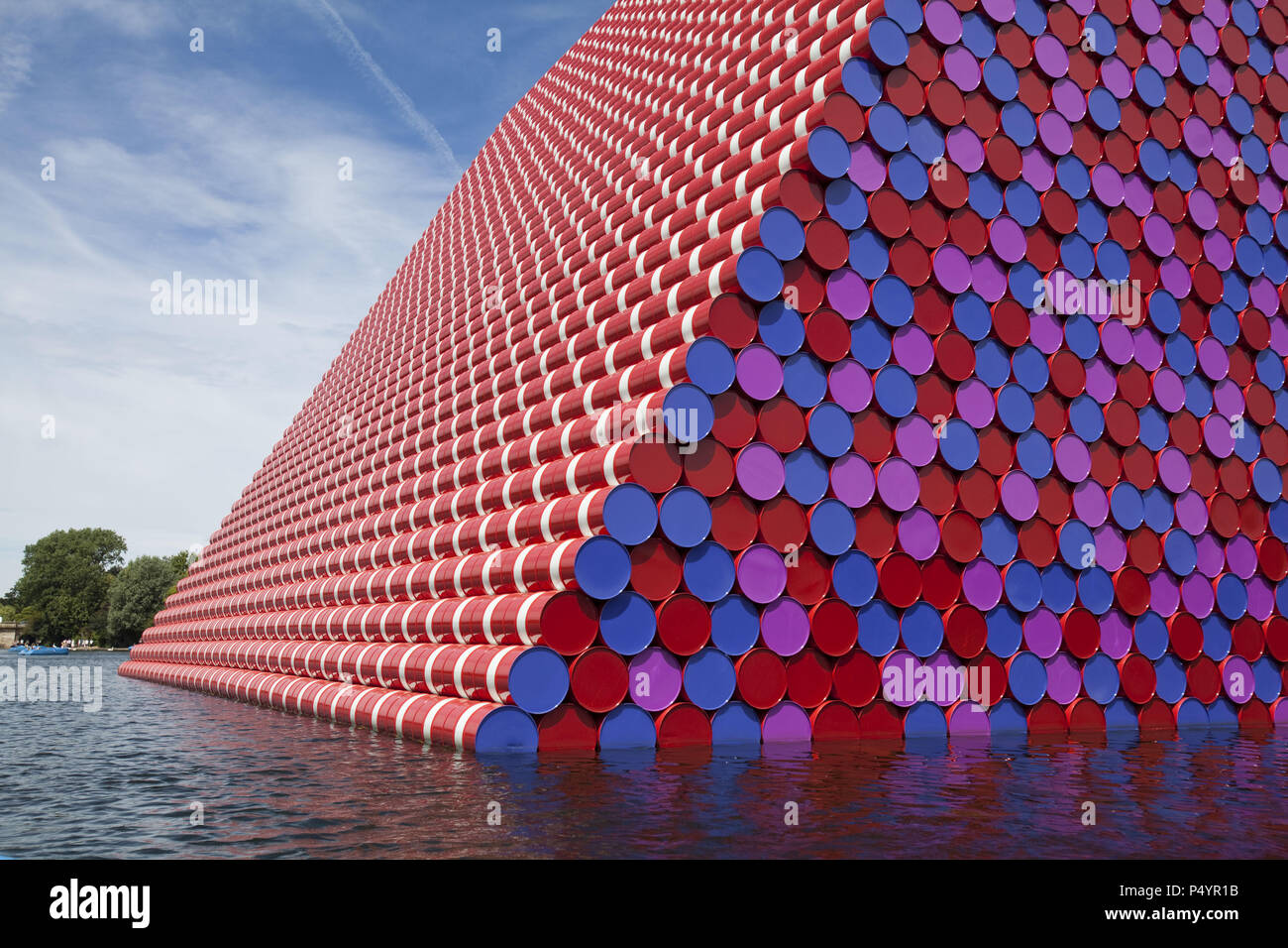 London, UK. 23 June 2018 The Mastaba, a temporary sculpture made of stacked barrels in Serpentine Lake in Hyde Park, is made by one of the world's most celebrated artists, famous for ambitious large scale works. Christo and his late wife Jean-Claude took an inspiration from ancient mastabas (benches) structures that originated in first urban civilisatons of Mesopotamia. Twenty metres in height, the structure consists of 7506 horizontally-stacked coloured barrels. The sculpture coincides with Serpentine Galleries exhibition of Christo and Jeanne-Claude's use of barrels in their work over th Cre Stock Photo