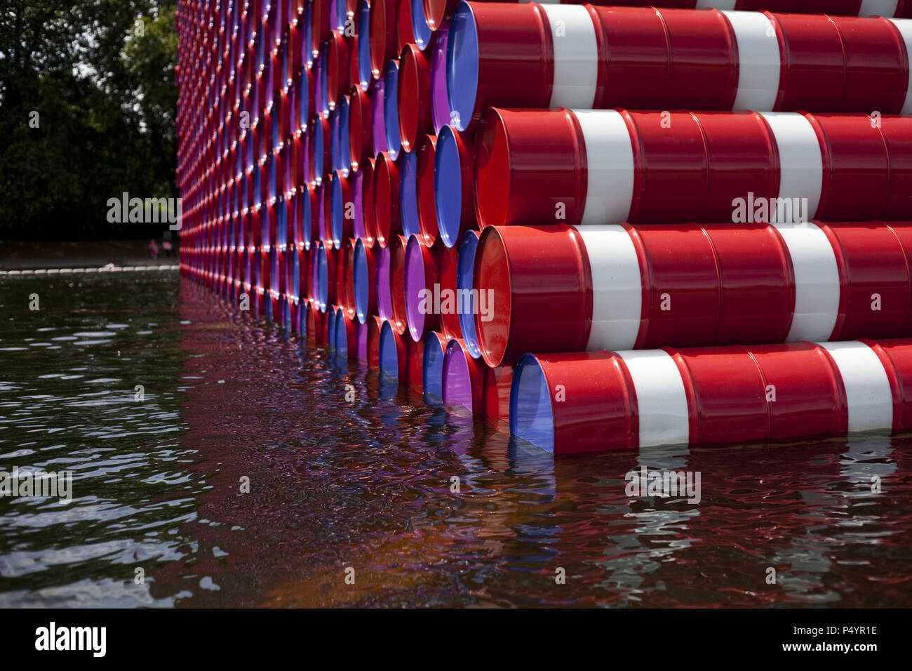 London, UK. 23 June 2018 The Mastaba, a temporary sculpture made of stacked barrels in Serpentine Lake in Hyde Park, is made by one of the world's most celebrated artists, famous for ambitious large scale works. Christo and his late wife Jean-Claude took an inspiration from ancient mastabas (benches) structures that originated in first urban civilisatons of Mesopotamia. Twenty metres in height, the structure consists of 7506 horizontally-stacked coloured barrels. The sculpture coincides with Serpentine Galleries exhibition of Christo and Jeanne-Claude's use of barrels in their work over th Cre Stock Photo