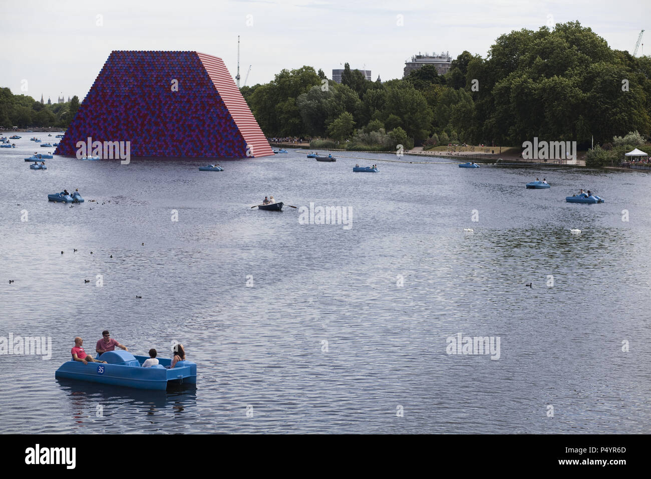 London, UK. 23 June 2018 The Mastaba, a temporary sculpture made of stacked barrels in Serpentine Lake in Hyde Park, is made by one of the world's most celebrated artists, famous for ambitious large scale works. Christo and his late wife Jean-Claude took an inspiration from ancient mastabas (benches) structures that originated in first urban civilisatons of Mesopotamia. Twenty metres in height, the structure consists of 7506 horizontally-stacked coloured barrels. The sculpture coincides with Serpentine Galleries exhibition of Christo and Jeanne-Claude's use of barrels in their work over th Cre Stock Photo