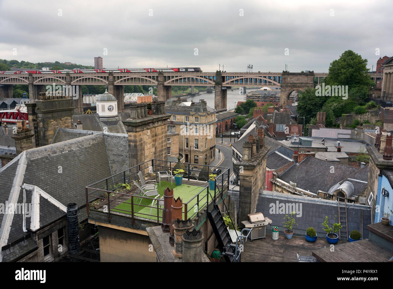 A view from the Tyne Bridge over Newcastle-upon-Tyne's roofs towards the High Level Bridge, with a train crossing. Stock Photo