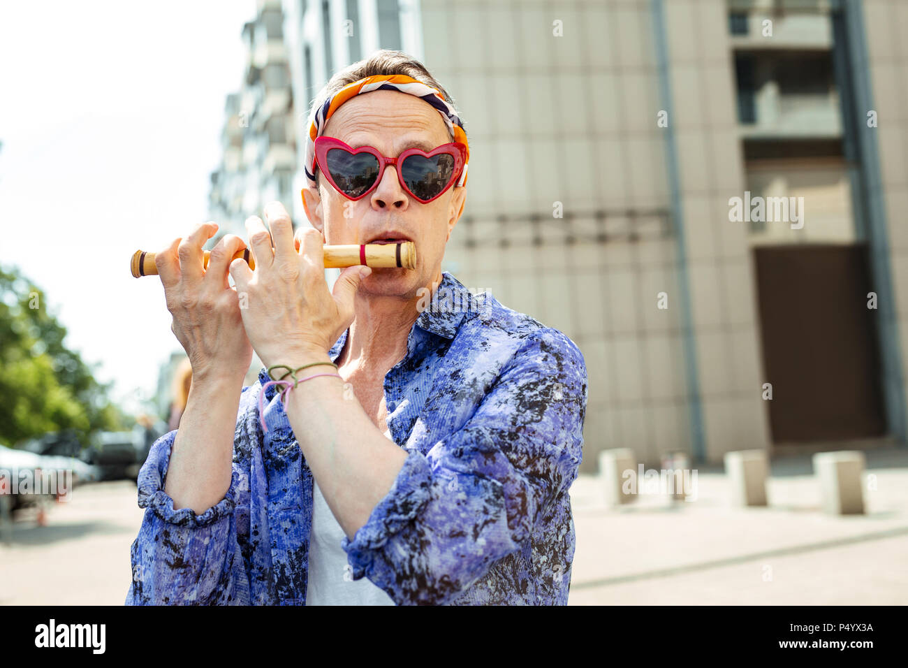 Flower-child wearing red heart glasses playing the harmonica Stock Photo