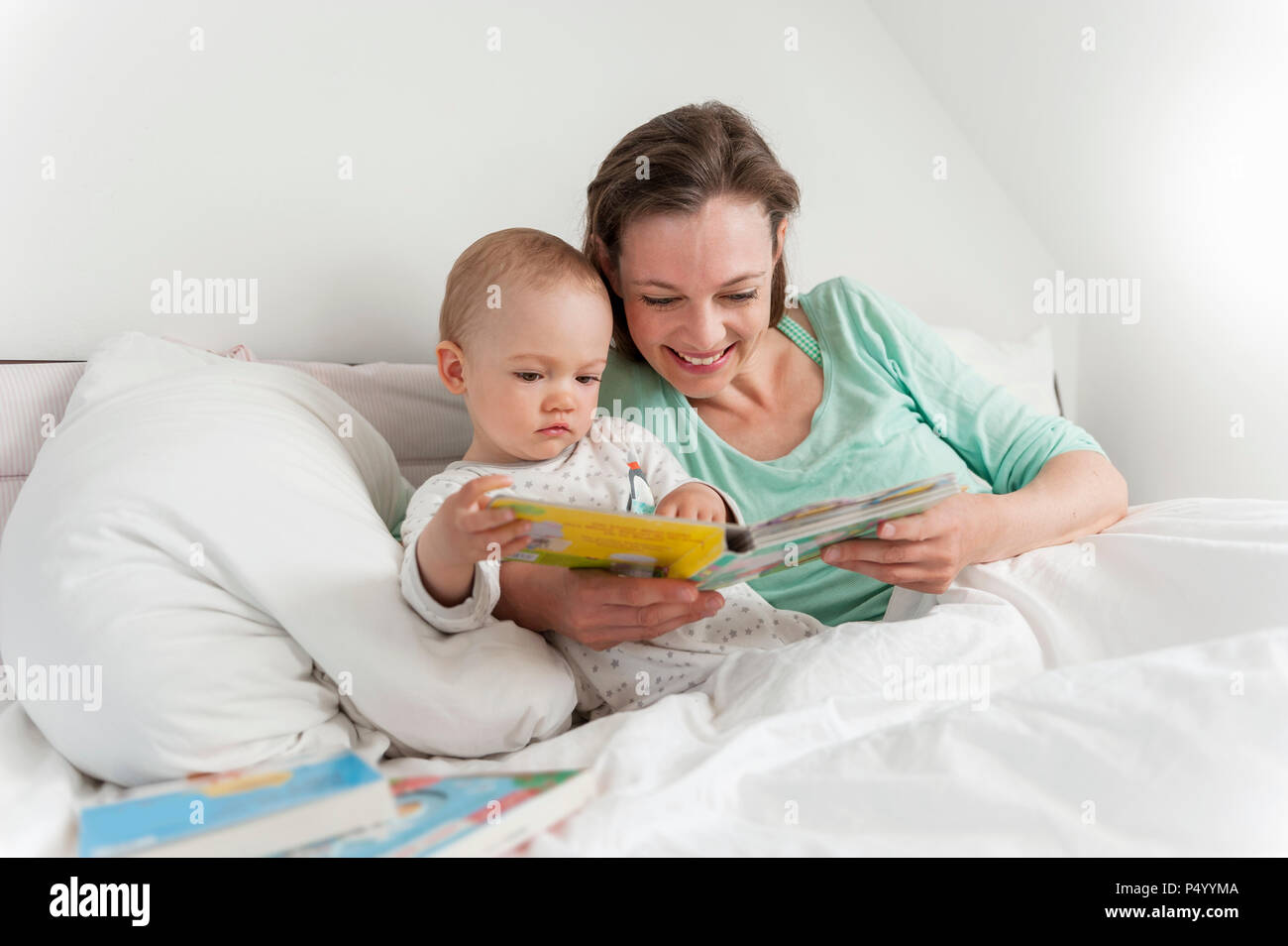 Mother and baby in bed reading picture book Stock Photo