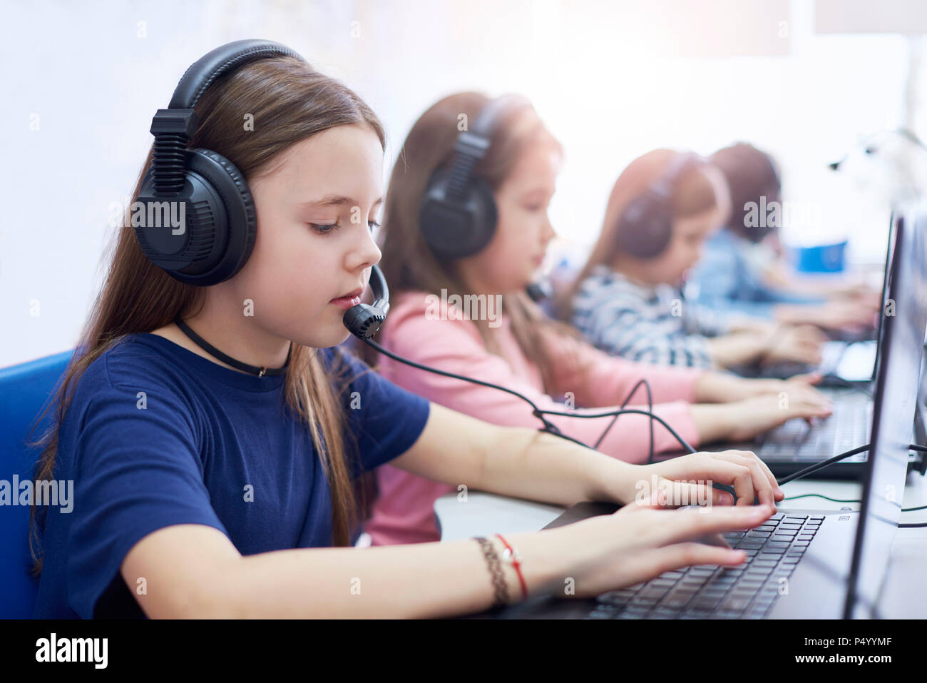 Pupils wearing headsets and using laptops in school Stock Photo