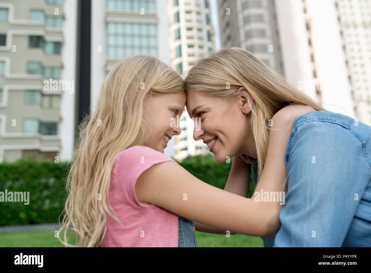Happy mother and daughter smiling at each other urban city garden Stock Photo