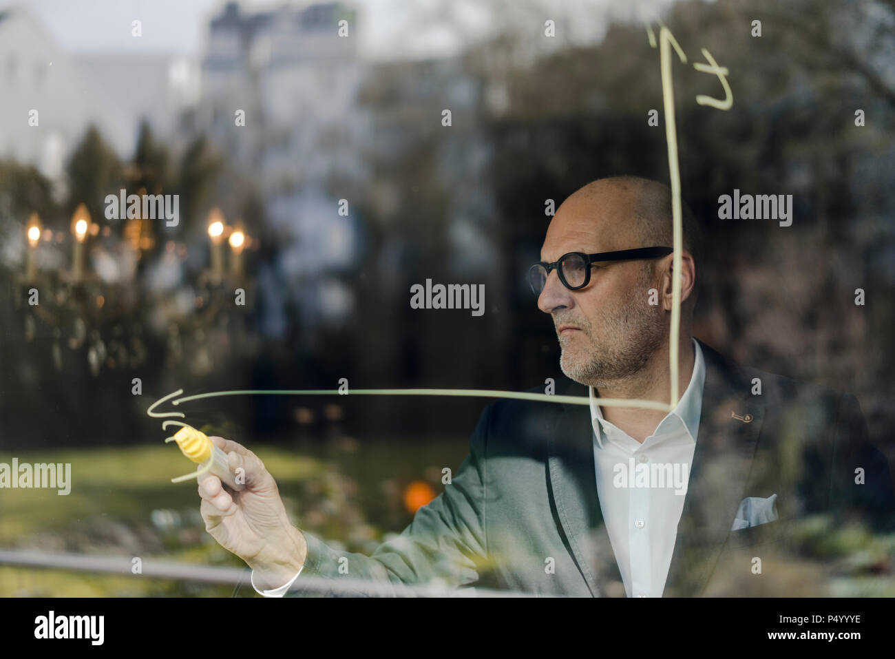senior businessman brainstorming, drawing formulas on window pane Stock Photo