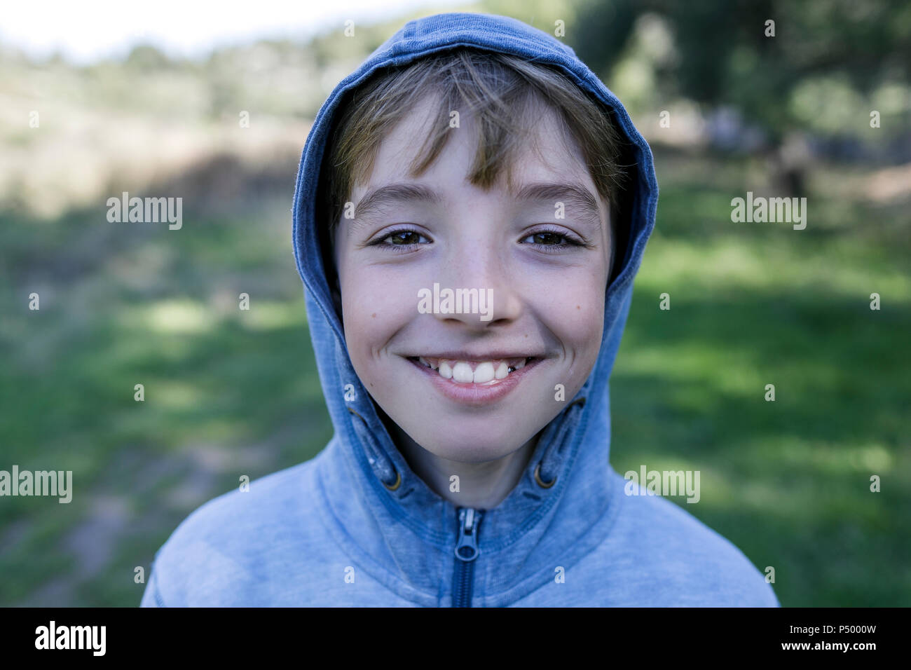 Portrait of laughing boy wearing blue hooded jacket Stock Photo