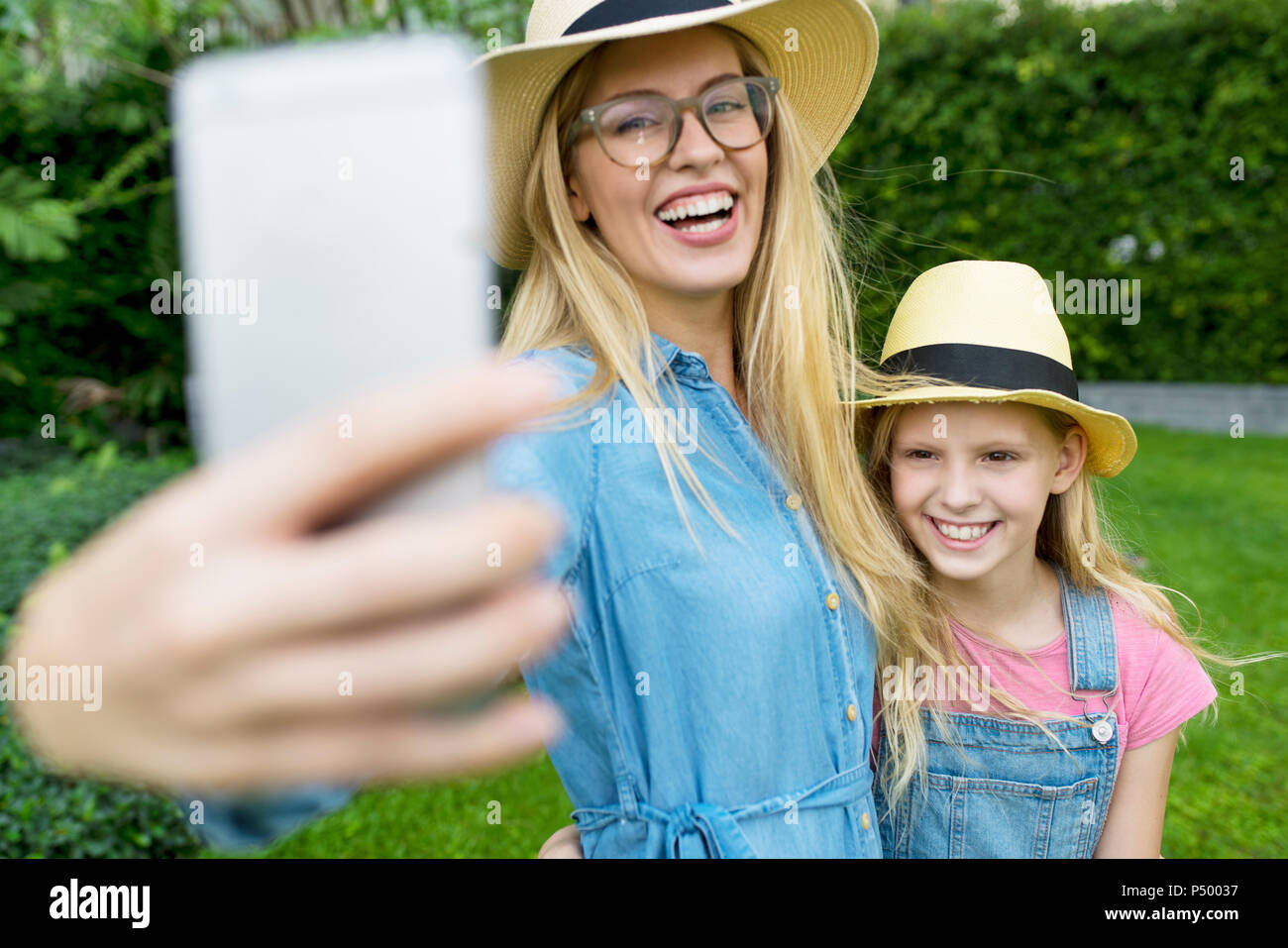 Happy mother and daughter taking a selfie in garden Stock Photo