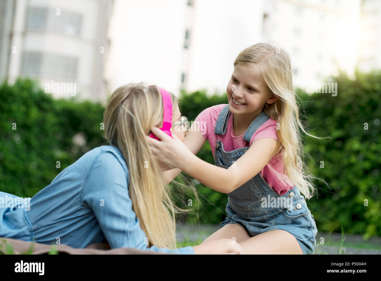 Happy mother and daughter listening to music together in garden Stock Photo