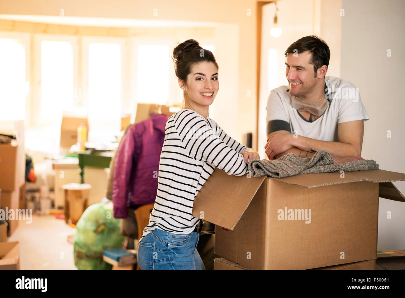 Happy couple moving house, standing by cardboard box Stock Photo
