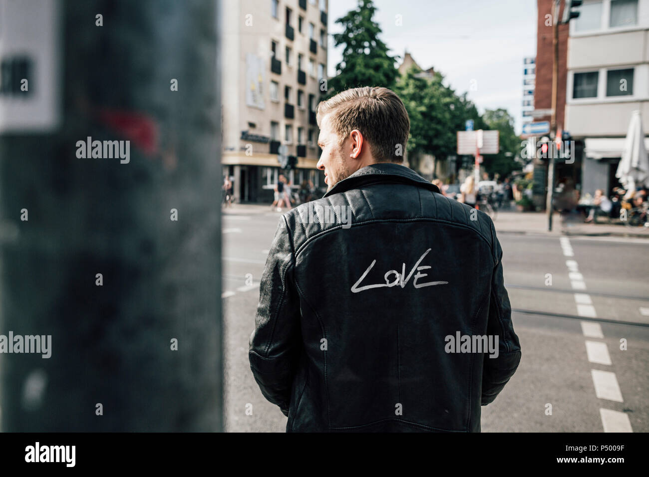 Back view of young man wearing black leather jacket with writing 'Love' Stock Photo