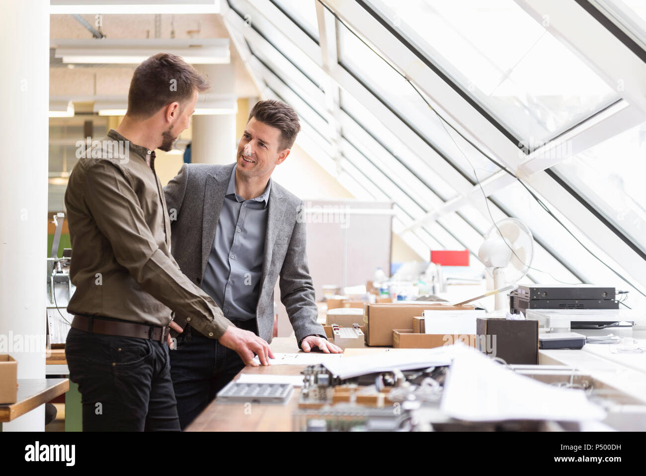 Two smiling businessmen with plan in factory Stock Photo - Alamy