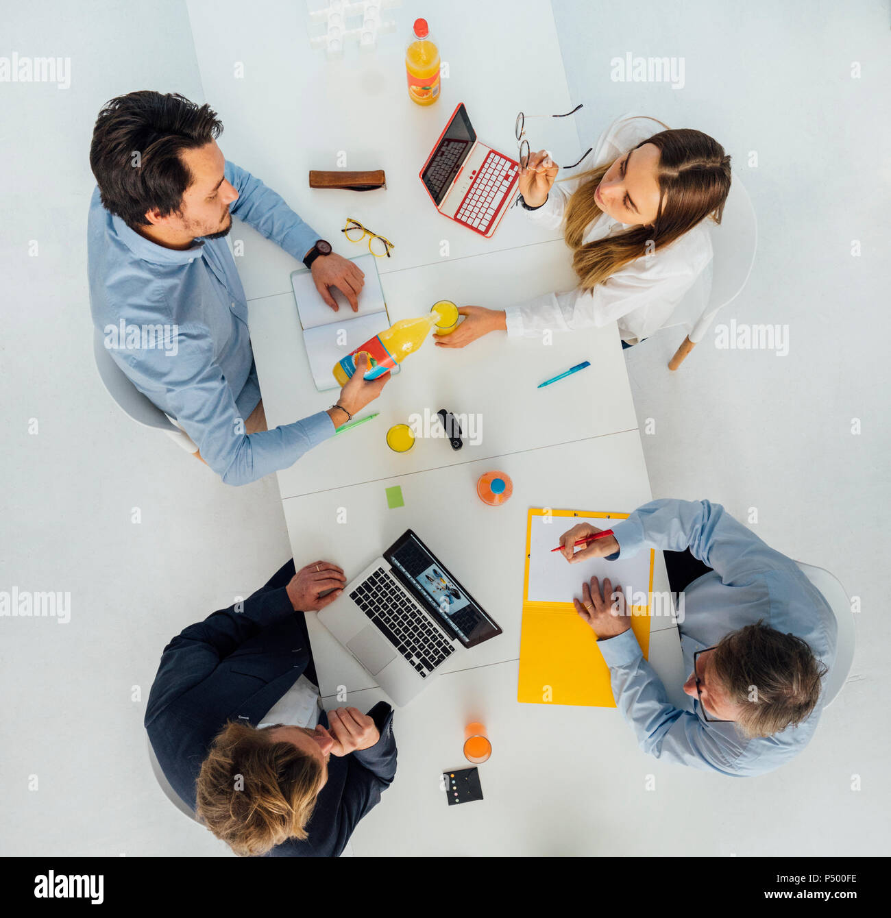 Four business people at meeting table in office, top view Stock Photo