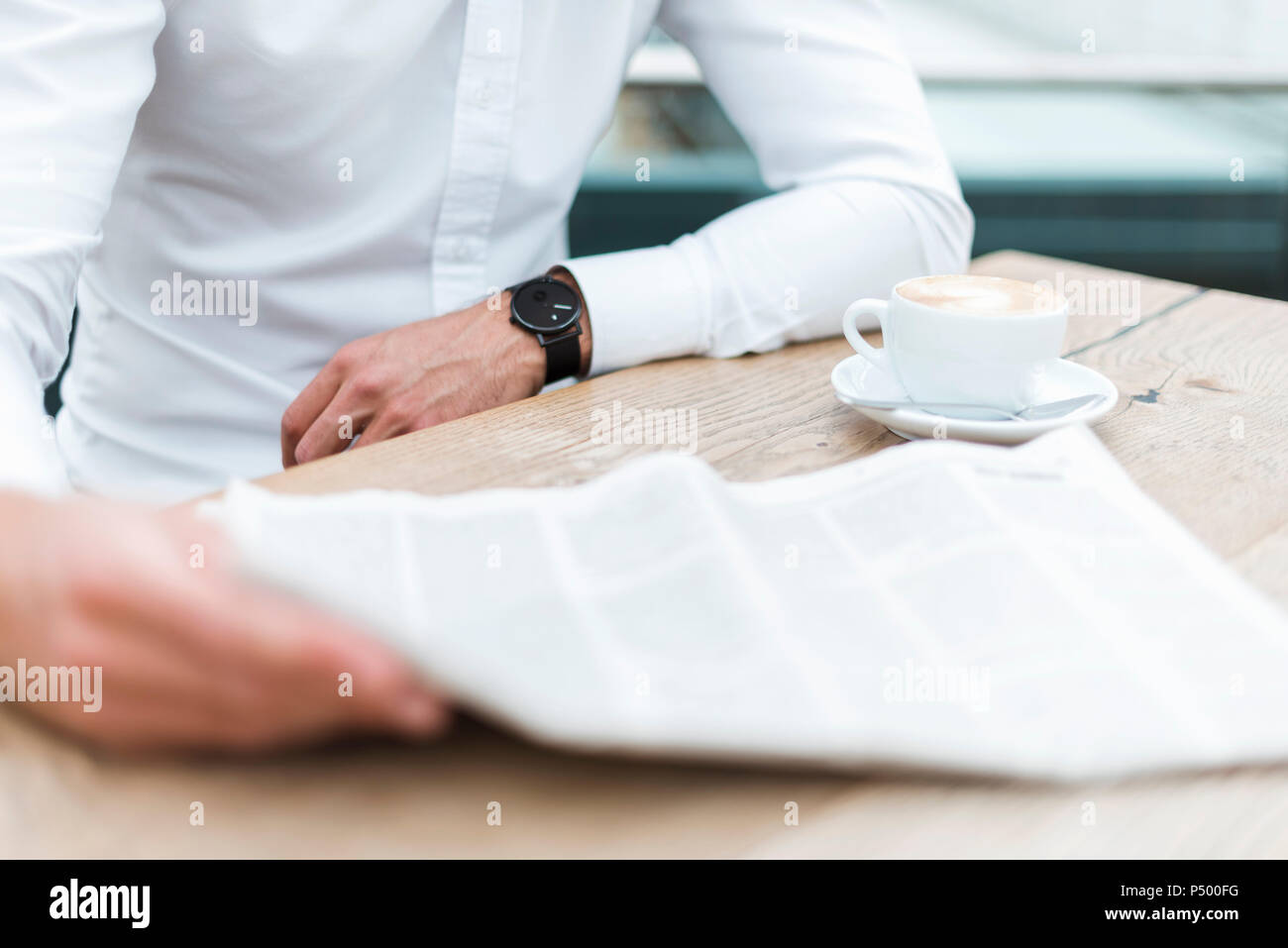Close-up of businessman reading newspaper in a cafe Stock Photo