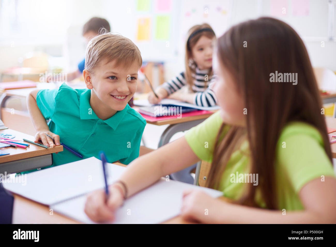 Schoolboy smiling at schoolgirl in class Stock Photo - Alamy