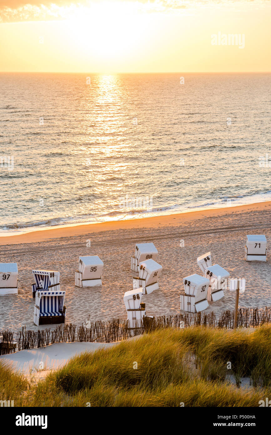 Germany, Schleswig-Holstein, Sylt, beach and empty hooded beach chairs at sunset Stock Photo