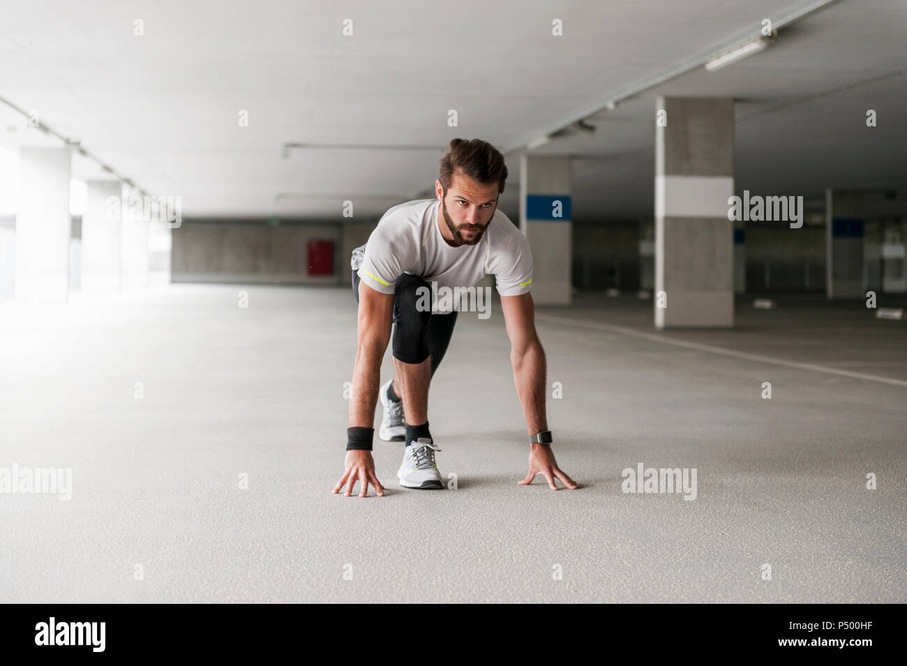 Athlete In Starting Position In Parking Garage Stock Photo